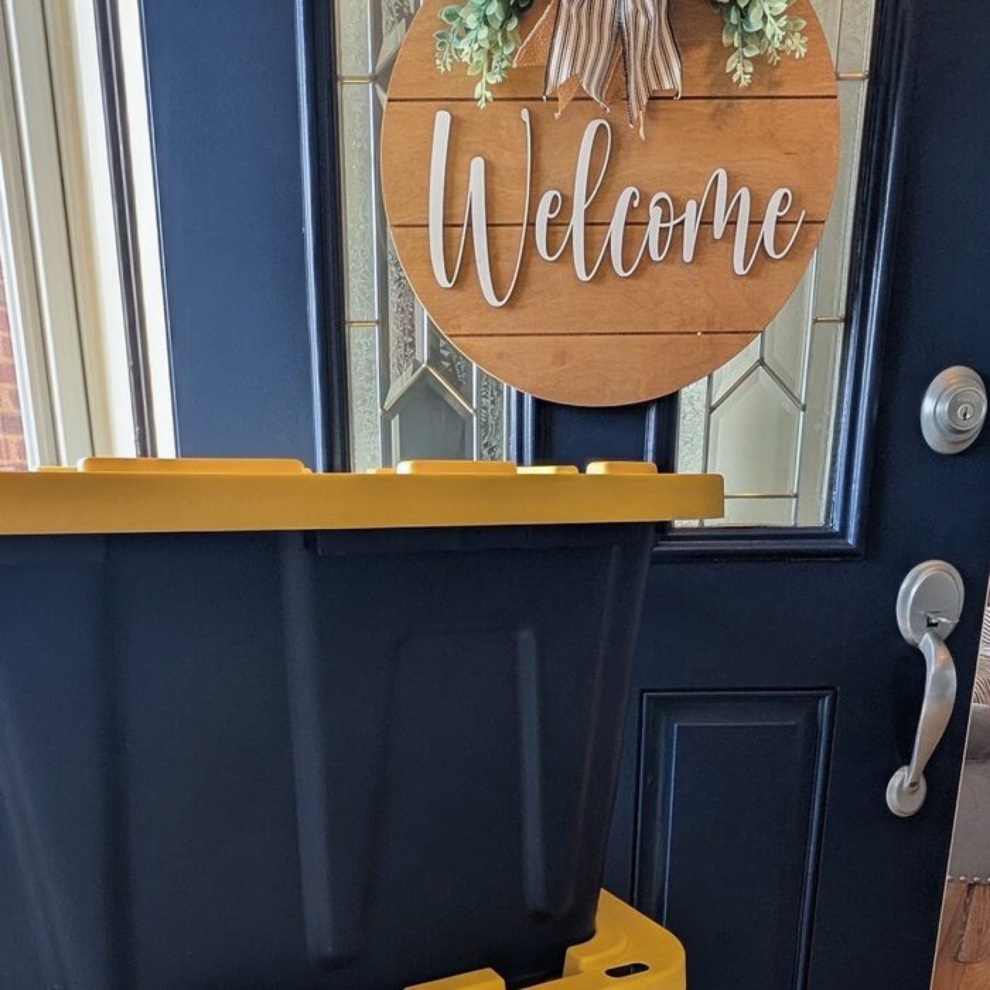 Navy moving totes with yellow lids stacked at a front door