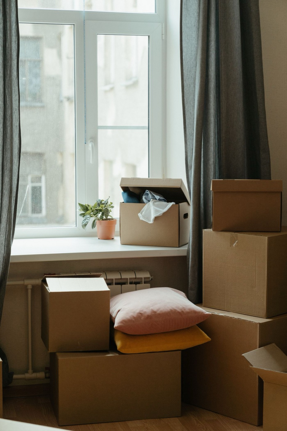 Packed boxes stacked by a window, ready to be collected